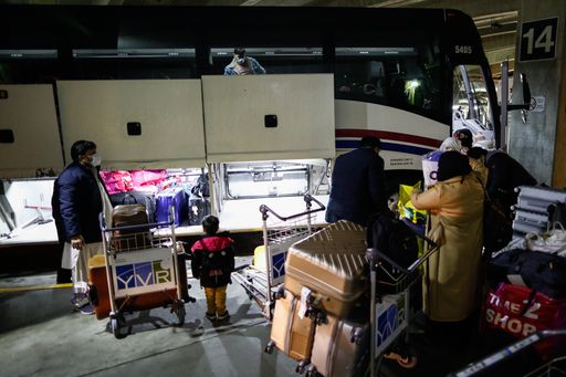 Families board a bus after landing in Vancouver on January 18, 2022.