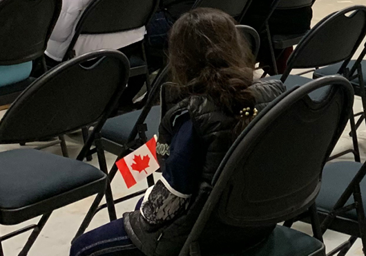 A young Afghan girl waits in the processing room in Toronto with a Canadian flag in hand, on December 2, 2021.