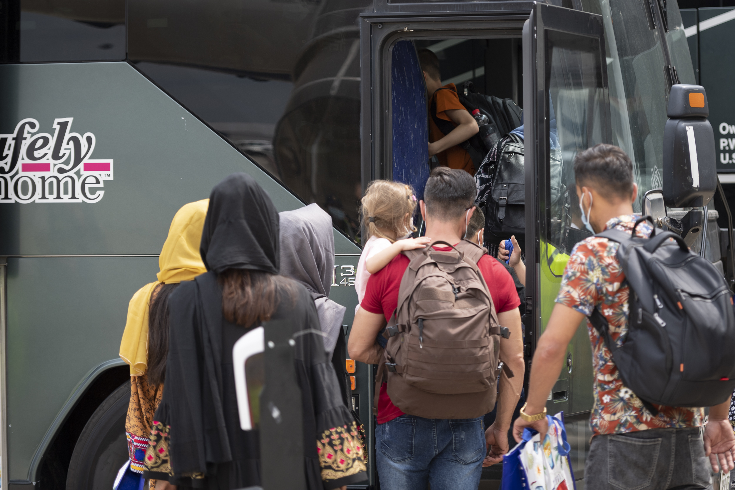 Families board a bus after landing in Toronto