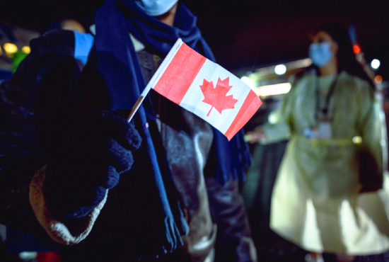 Un réfugié avec un drapeau canadien à la main après son arrivée à St. John’s