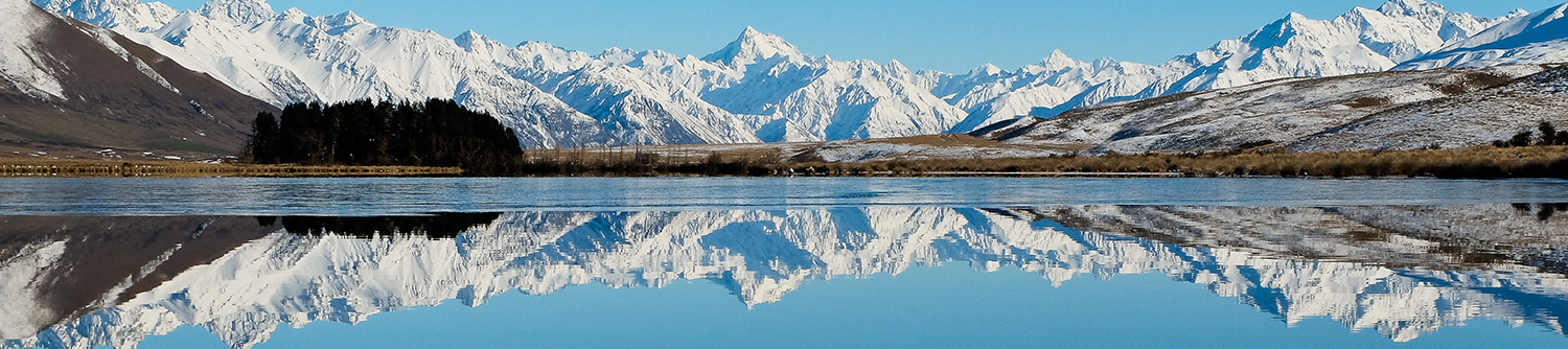 Snow-capped mountains behind a crystal clear lake in New Zealand
