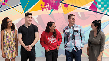 Un groupe de jeunes adultes debout et riant ensemble.