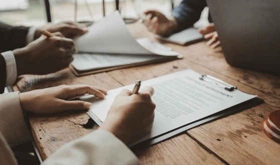 Close-up of a desk with agendas and three coworkers