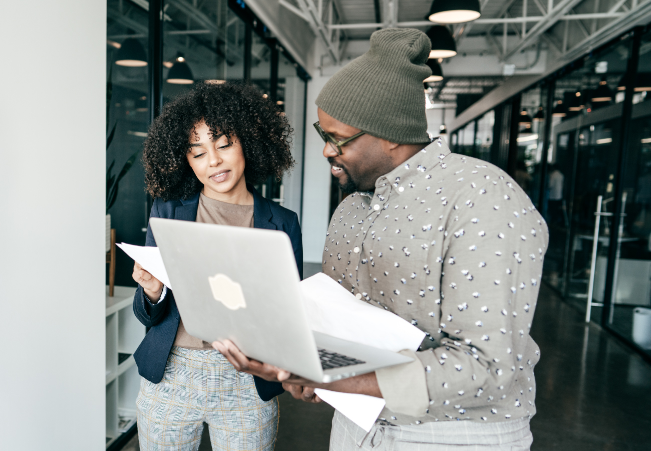 Two working people talking with papers and a laptop