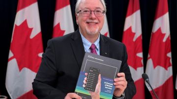 The Ombudsperson smiling while holding the 2025-2026 annual report in his hands.