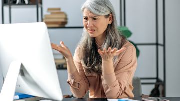 Woman confused with her hands up looking at desktop screen