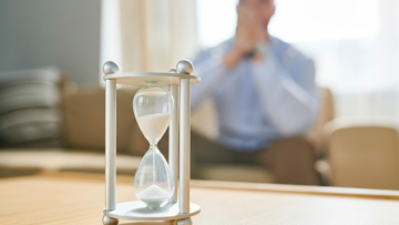 Hourglass on table, person blurred background