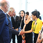 Prince of Wales shaking hands with a young woman