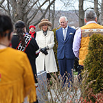 Le prince de Galles et la duchesse de Cornouailles debout avec des chefs autochtones lors d'un moment solennel.