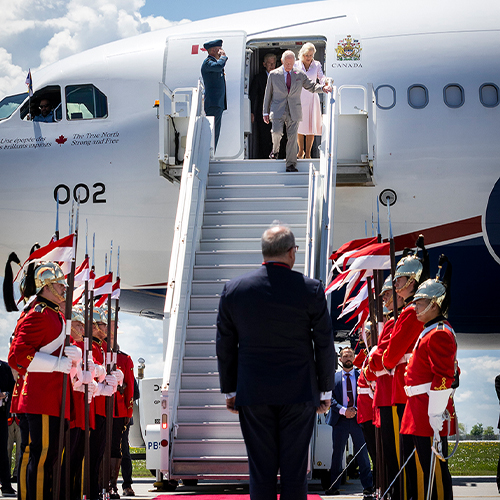 Le roi Charles III et la reine Camilla sortent d'un avion. Une personne est debout au pied des escaliers de l'avion.