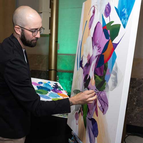 An artist paints on a canvas.