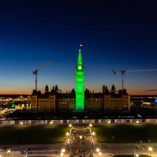 The Peace Tower, which rises from the Centre Block (or Parliament Building), is illuminated in emerald green on a cloudless, clear night.