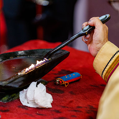 An Inuk Elder sits by a qulliq, a traditional Inuit oil lamp.