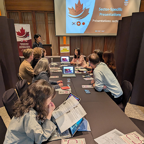 Un groupe de personnes assises à une longue table regardant une présentation.