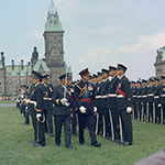 Le duc d'Édimbourg marche devant des membres du Royal Canadian Regiment qui se tiennent au garde-à-vous à l'extérieur, sur la Colline du Parlement.