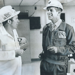 Black and white image of The Duke of Edinburgh talking with mine superintendent Robert Donahue. They are wearing mining worker uniforms and hard hats.
