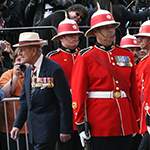 Le duc d'Édimbourg fait l'inspection de la garde. Des officiers vêtus de leur uniforme rouge et blanc sont au garde à vous. 