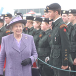Queen Elizabeth II walking by young cadets that are standing at attention.