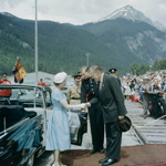Queen Elizabeth II shaking hands with Justice Minister Davie Fulton in front of a crowd.