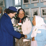 Three Doukhobor women wearing traditional headscarves meet Her Majesty The Queen, who is shaking hands with one of them.