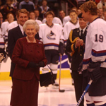 Queen Elizabeth II talking to hockey players on an indoor skating rink.