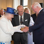 Queen Elizabeth II accepting a gift from Governor General David Johnston, as the Duke of Edinburgh looks on.