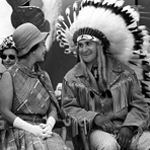 Black and white image of Queen Elizabeth II sitting with Chief Leonard Pelletier. He is wearing traditional regalia.