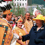 Queen Elizabeth II shakes hands with an Indigenous Chief in front of a group of people.
