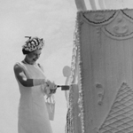 Black and white image of Queen Elizabeth II cutting a giant cake.