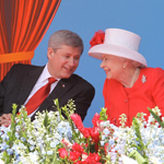 Queen Elizabeth II and Prime Minister Stephen Harper sitting next to each other and talking.