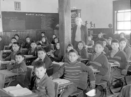 Élèves cris à leurs pupitres avec leur professeur dans une salle de classe, Pensionnat indien de All Saints, Lac La Ronge (Saskatchewan), mars 1945
