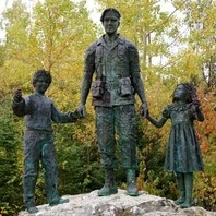 A statue showing three figures standing on a rock. The figures are a soldier holding hands with two children, a boy and a girl.