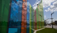 Photo of the artwork which is an enclosure created by large, multicoloured, transparent glass walls.