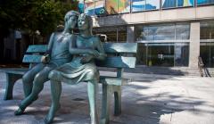 Photo of a sculpture of a young man and young woman cuddling on a bench.