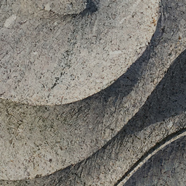 A tall tapered standing stone is shown in front of a background with grey swirls. The stone is inscribed with writing and designs.