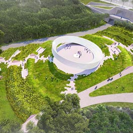 A birds-eye view of the design. In the middle, we see a large white ring that has one side touching the ground and the other side suspended in the air.  It is surrounded by light coloured pathways and lush green landscaping.  In the upper right, we see a concrete bridge-walkway.