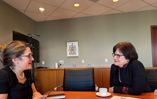Deborah Lyons en conversation avec Chrystia Freeland devant une tasse de café, dans une salle de réunion