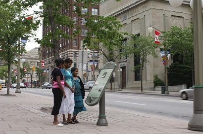 Une famille lit un panneau d'interprétation sur le boulevard de la Confédération.