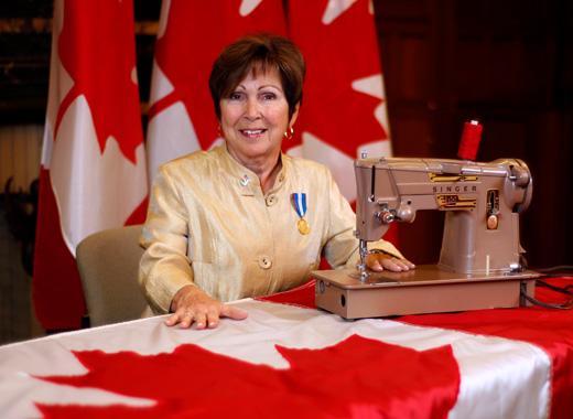 Joan O’Malley avec une machine à coudre et des drapeaux canadiens