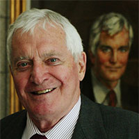 John Turner stands in front of a portrait of himself. 