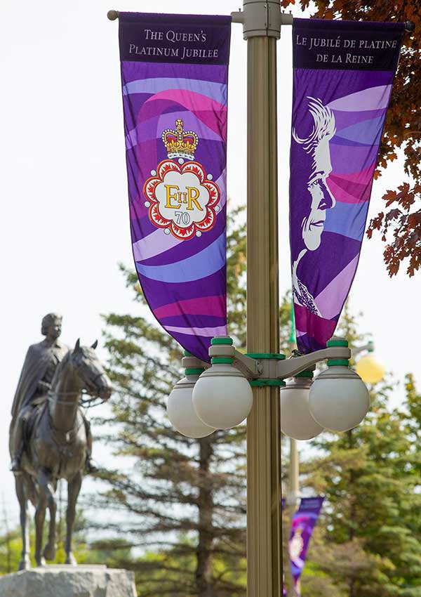 View of a street with people walking and lampposts, on each of which are hung banners in shades of purple.