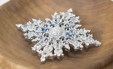 Image de la broche en forme de flocon de neige soulignant le Jubilé de saphir : les saphirs sont au centre, entourés de diamants en forme de flocon de neige.