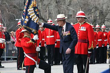 Le prince Philip tient un drapeau en présences de militaires.