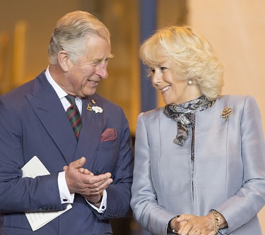 A close-up shot of King Charles III and the Queen Consort looking at each other, all smiles.