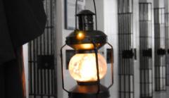 Photo of guide carrying old-fashioned lantern past jail cells