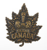A bronze badge in the shape of a maple leaf.