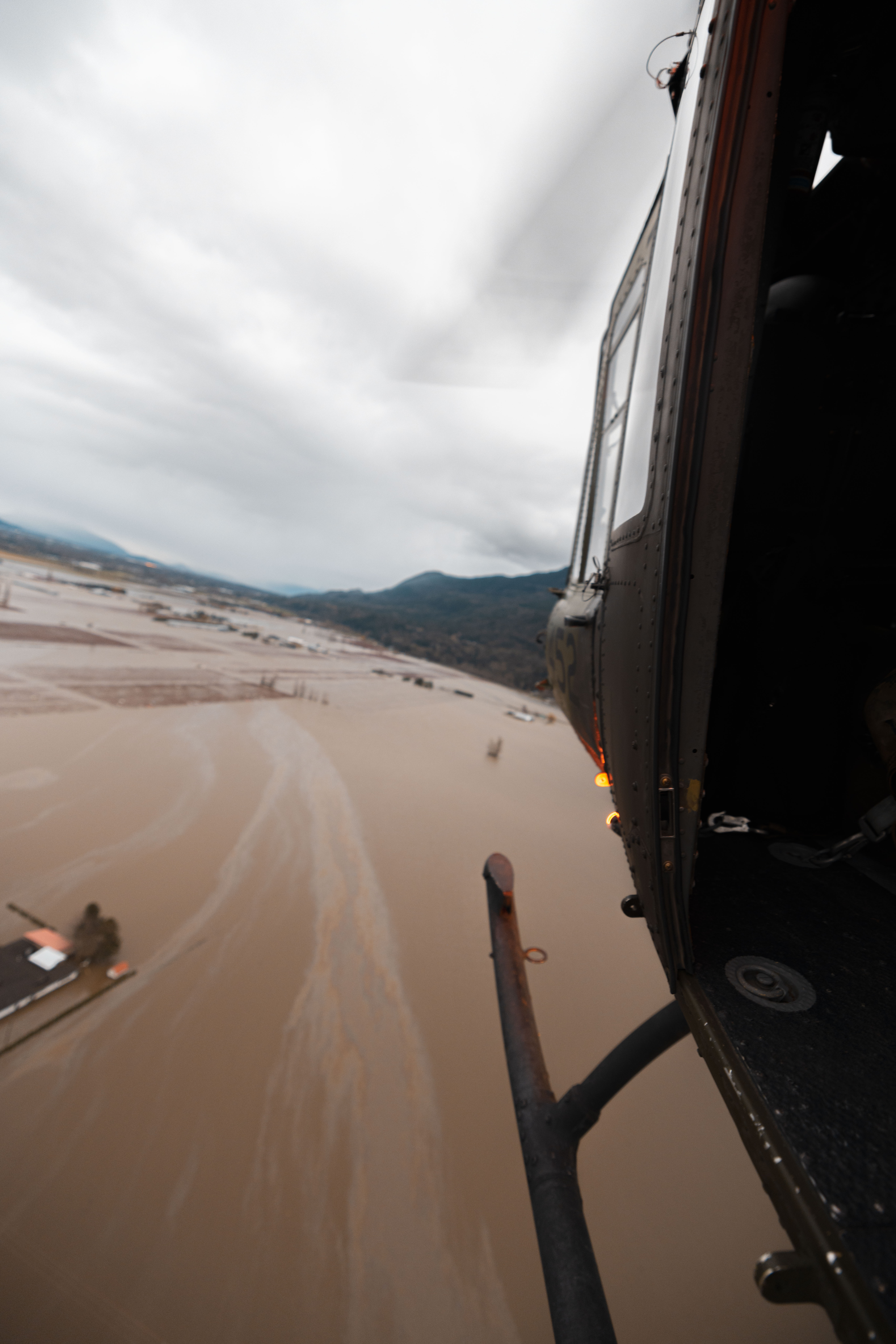 A helicopter flies over flooded terrain