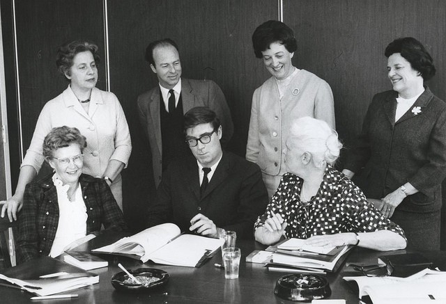Autour d'une table, le Premier ministre Pirre-Elliott Trudeau, le ministre responsable de la Condition féminine et 5 femmes signent des documents