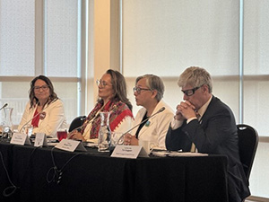 Tim Hodgson sitting at the end of a table with three other Summit participants to his right