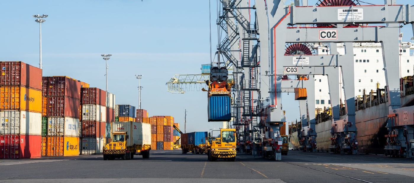 Cargo containers, two transportation trucks and terminals on a port